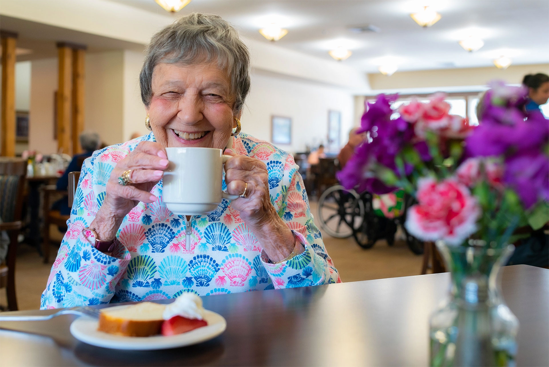 Smiling elderly woman enjoying coffee in a cozy setting.